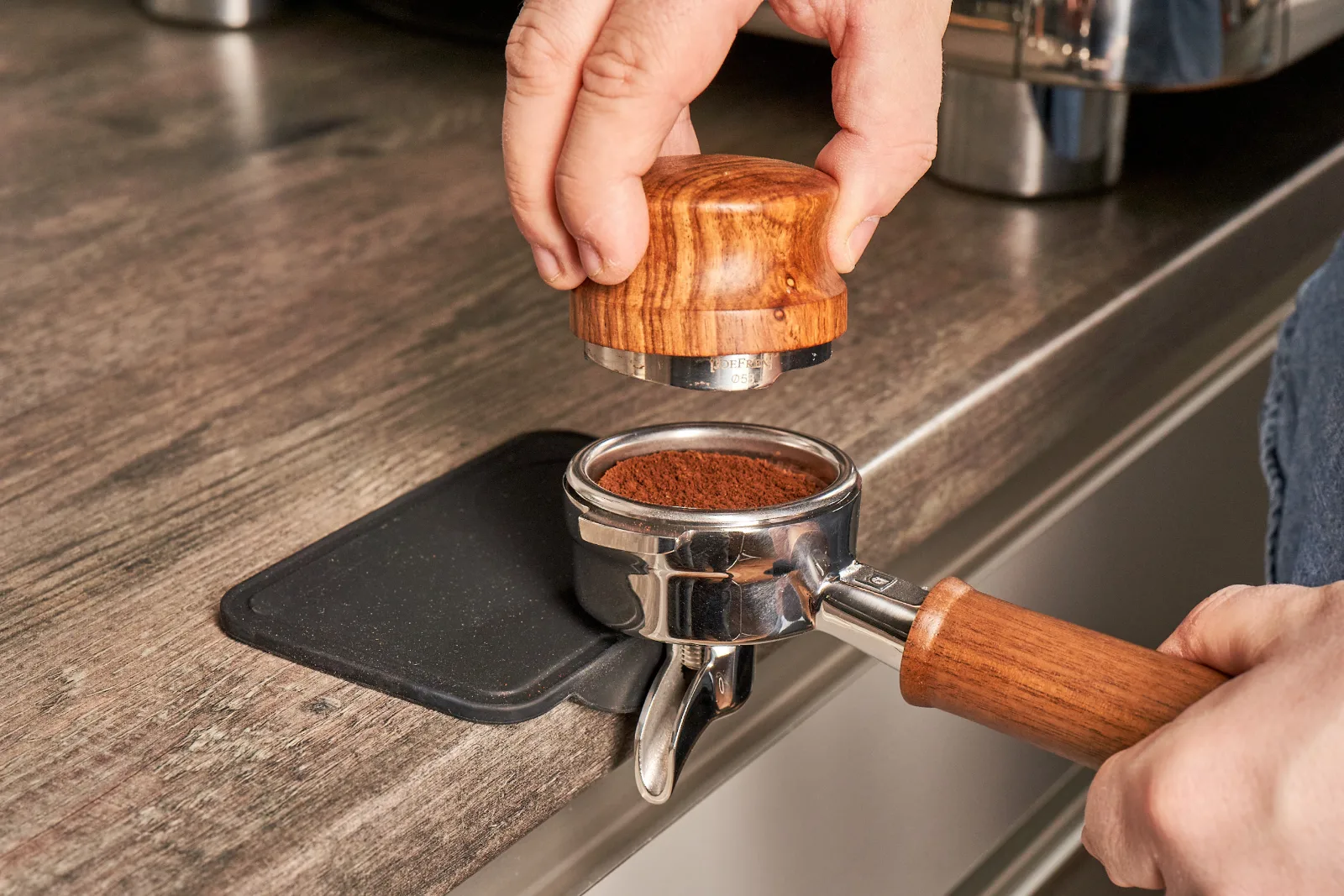 Barista drückt Kaffeemehl mit dem Tamper im Siebträger an
