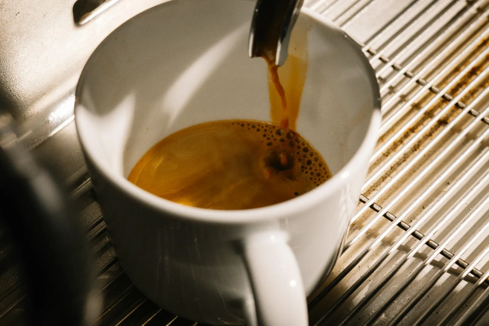 Espresso läuft aus dem Siebträger in eine weiße Tasse