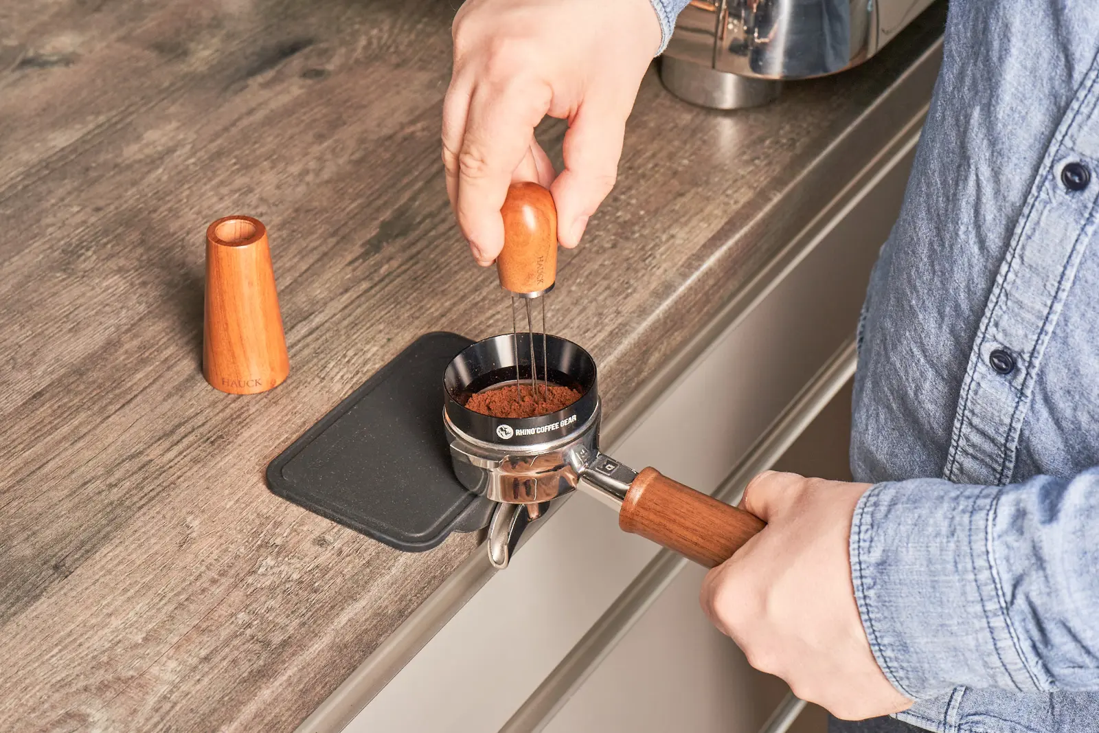 Barista verteilt Kaffeemehl im Siebträger mit einem Distributionswerkzeug