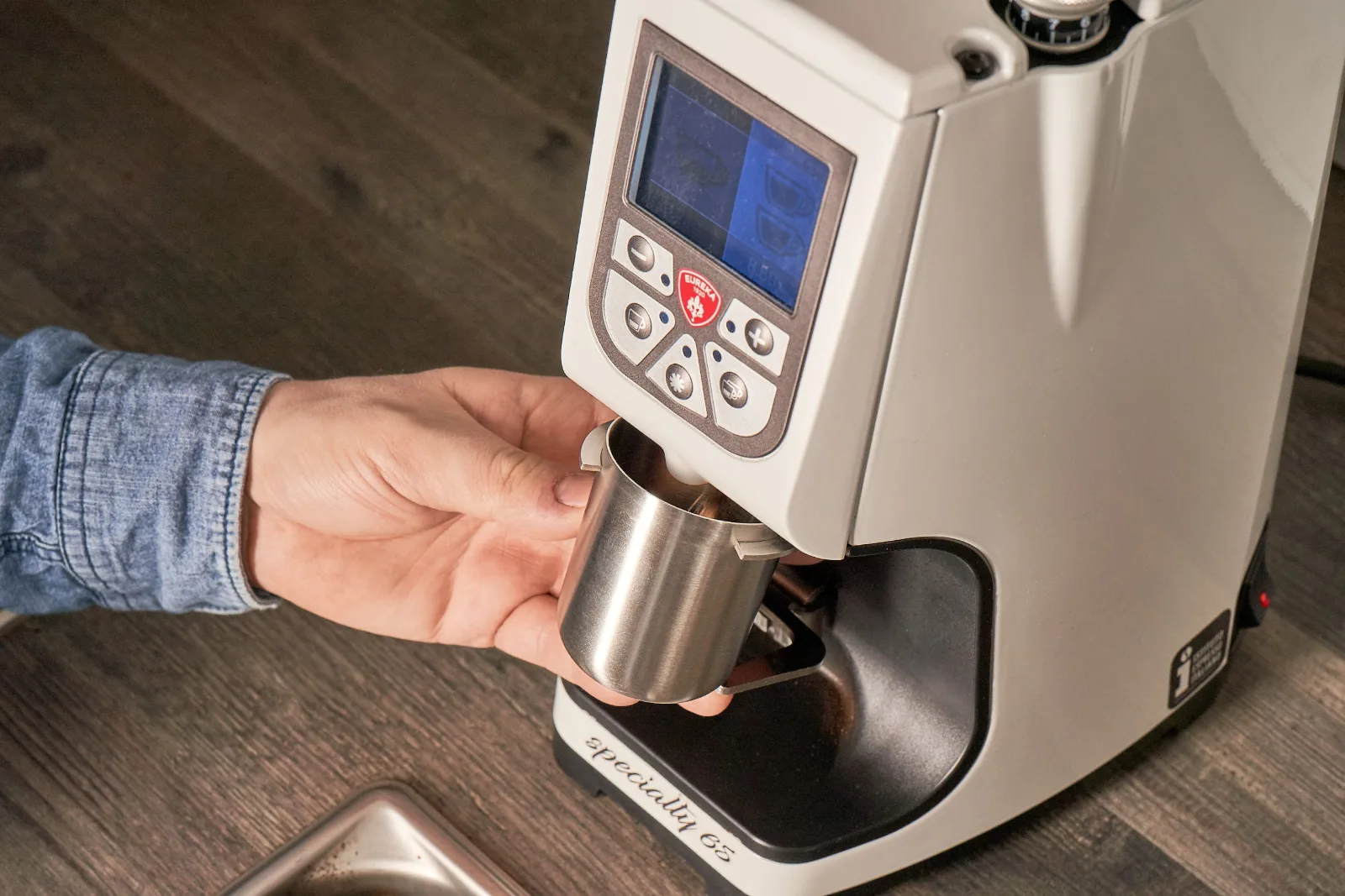 Kaffee wird aus der Espressomühle in einen Dosierbecher gemahlen