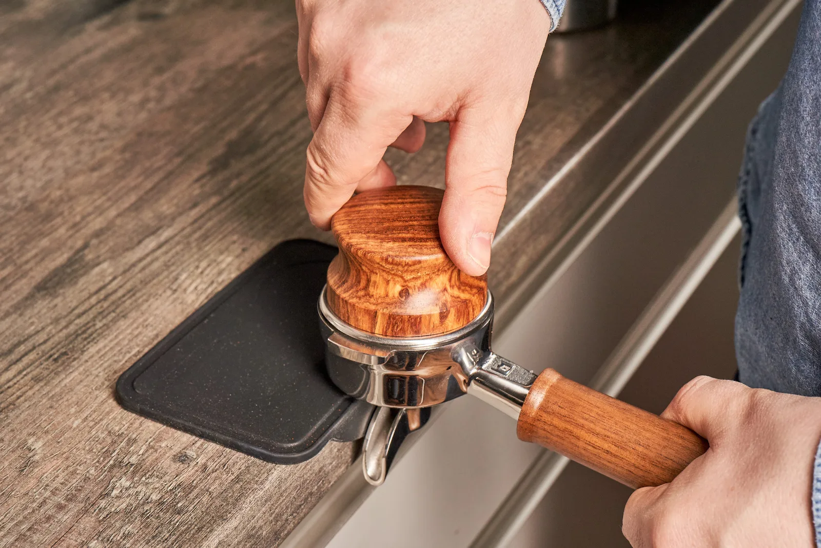 Barista tampert Kaffee im Siebträger an der Bar