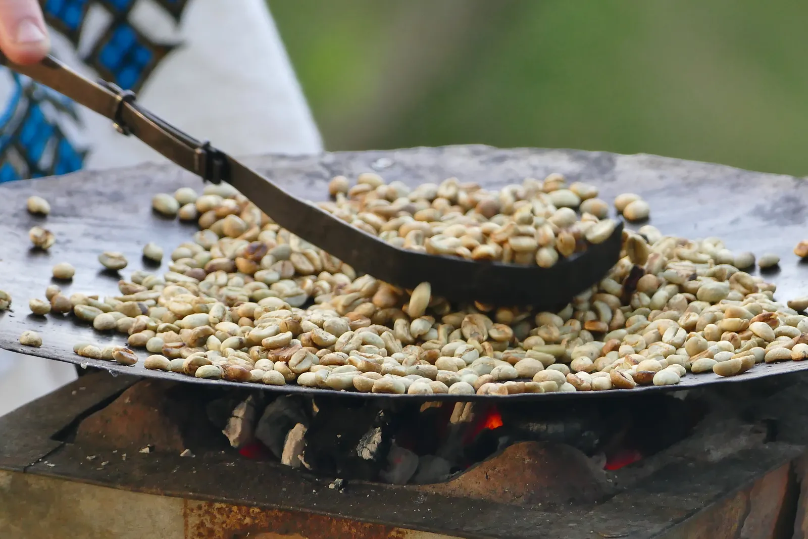 Rohkaffee wird in einer offenen Pfanne über Holzkohle geröstet