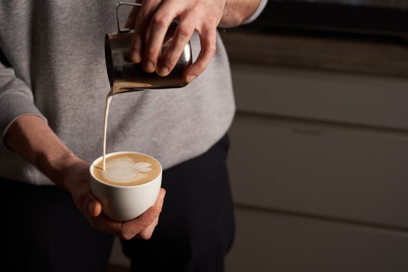 Milchschaum wird in einen Cappuccino gegossen