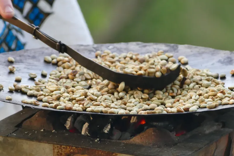 Kaffee wird in einer Pfanne über offenem Feuer geröstet